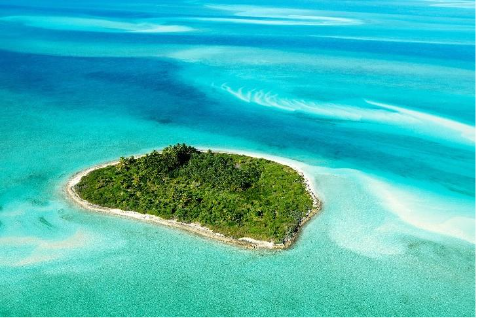 Tropical Bahamian island surrounded by turquoise waters, white beaches, and lush green vegetation.