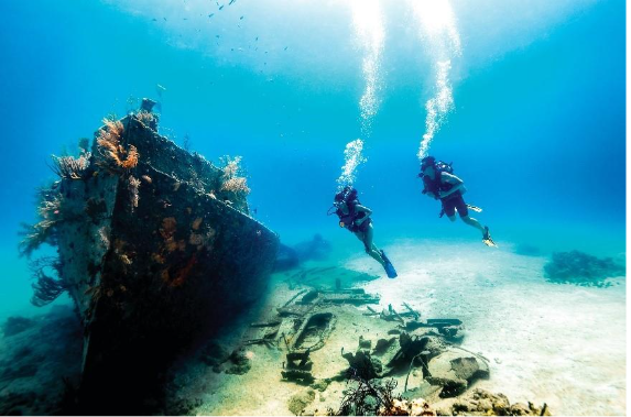 Two snorkelers exploring colorful coral reefs and tropical fish in crystal-clear waters of the Bahamas.